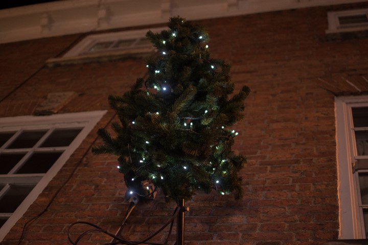 small christmas tree with lights on the side of a building